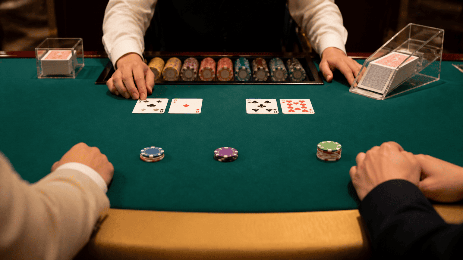 Bàn baccarat với các lá bài và phỉnh trên mặt nỉ xanh
